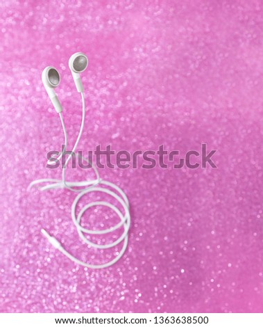 audio headphones on pink shiny background. beautiful creative composition with white little headphones. atmosphere minimalism concept of digital music.
