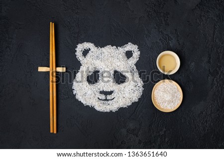 Panda, symbol of China. Face of panda  made of white grain rice on dark background. Asia culture creative design. Kawaii style