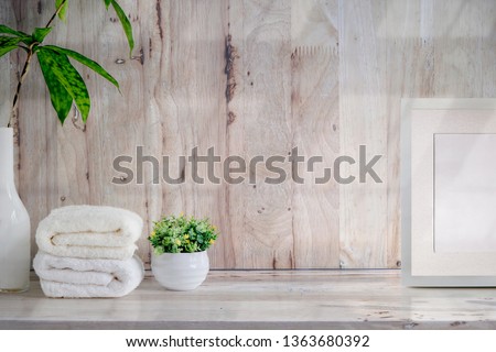 Mockup bath towels , blank wooden poster and houseplant on wooden table with copy space.