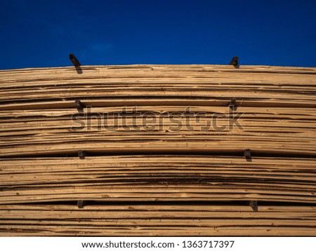 Heap of wooden boards in sawmill or in a warehouse. Storage of a large number of the sawn boards for sale. Production of wooden construction materials. Structure, texture, background
