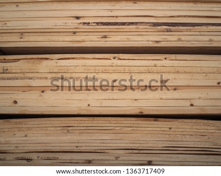 Heap of wooden boards in sawmill or in a warehouse. Storage of a large number of the sawn boards for sale. Production of wooden construction materials. Structure, texture, background