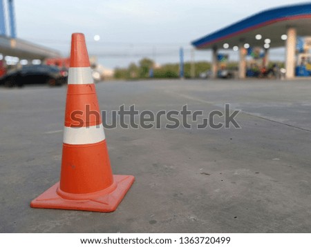 The red rubber cone has a backdrop, a gas station, a blurred background.