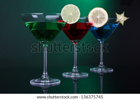 Alcoholic cocktails in martini glasses on dark green background