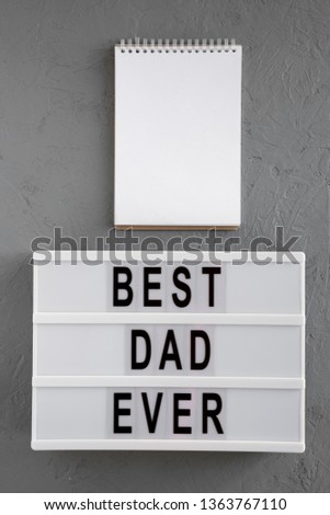 'Best dad ever' words on modern board, blank notepad over gray background, top view. Overhead, from above, flat lay. 