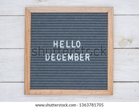 English text Hello December on a letter Board in white letters on a gray background. letter Board on white wooden background