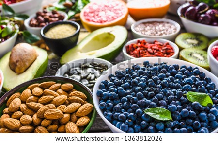 Bowl with almonds, bilberry, fresh fruit and other healthy food. Organic breakfast with vegetarian nutrition. Super foods collection on table. Royalty-Free Stock Photo #1363812026