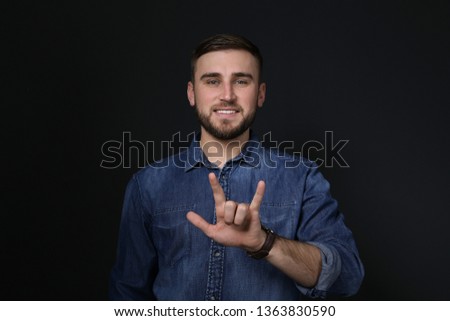 Man showing I LOVE YOU gesture in sign language on black background