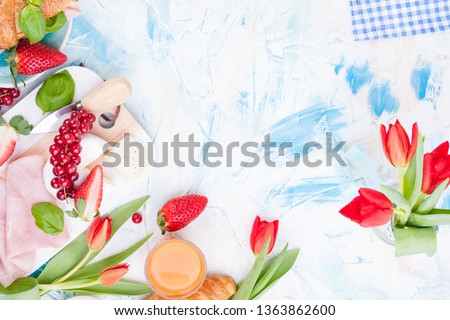 Breakfast or a dinner table with various delicacies for Easter meals. Fresh strawberries and currants with soft cheese and red spring tulips. Drinks and snacks for the holiday. Top view,
