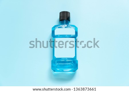 Mouthwash bottle with blank label for oral hygiene routine on light blue background. Mouth rinse liquids help to against bad breath, cavities and plaque. Dental care product. Top view. Royalty-Free Stock Photo #1363873661