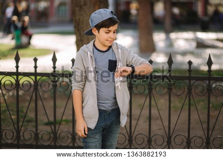 Boy is looking at the watch. Teenage boy walking in the city