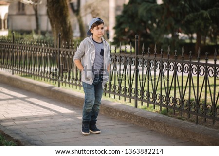 Cute boy walking in the city. Stylish teenage boy outside