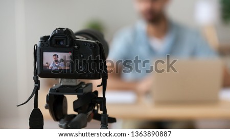 Close up successful man recording video, using digital camera in office or at home, successful freelancer, modern blogger, business coach making content, using professional equipment