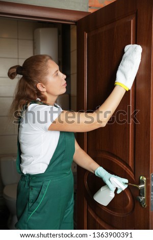 Professional janitor cleaning restroom door at home