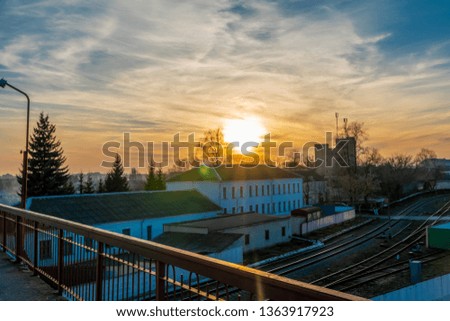Railway station against beautiful sky at sunset. Industrial landscape with railway, colorful blue sky with red clouds, sun, trees. Railway junction. Heavy industry. Spring evening
