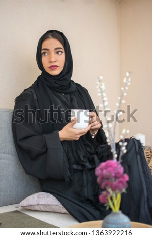 Beautiful young muslim woman drinking coffee at home