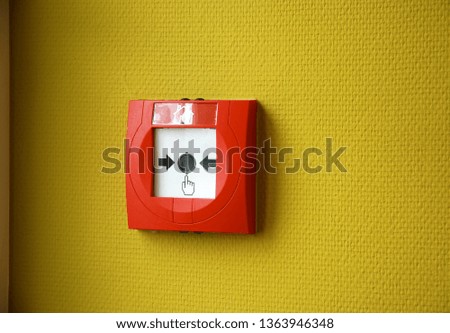 Fire alarm button on a yellow wall