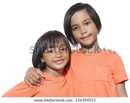 Asian sisters arms around on plain background