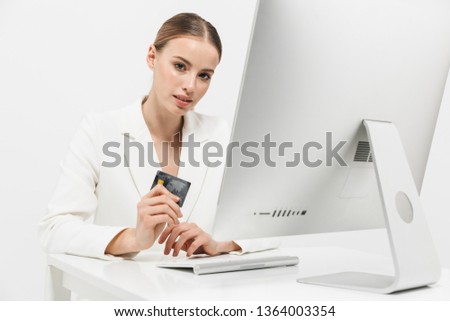 Image of a beautiful amazing woman sitting isolated over white wall background using pc computer holding credit card.