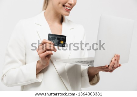 Cropped image of a beautiful happy amazing woman posing isolated over white wall background using laptop computer holding credit card.