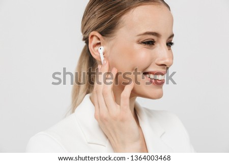 Image of a beautiful amazing woman posing isolated over white wall background listening music with earphones.