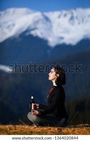 Beer yoga. Young woman doing yoga exercise in beautiful mountains
