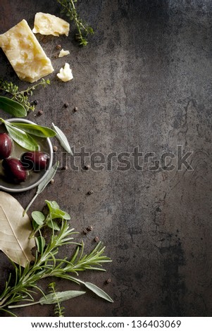 Food background with parmesan cheese, fresh herbs and olives, over dark slate.  Lots of copy space. Royalty-Free Stock Photo #136403069