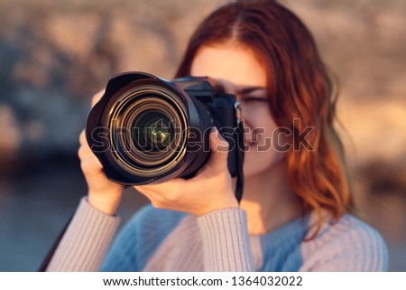 A woman with a camera in her hands in nature takes pictures of the rest