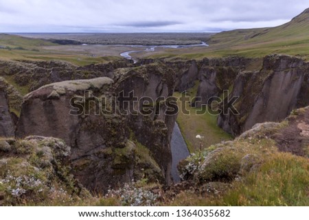 Deep gorge, at the bottom of which flows a mountain river and goes into a lava field covered with moss. Picture taken in Iceland