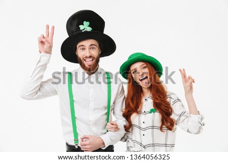 Happy young couple wearing costumes, celebrating St.Patrick 's Day isolated over white background, having fun together, peace gesture