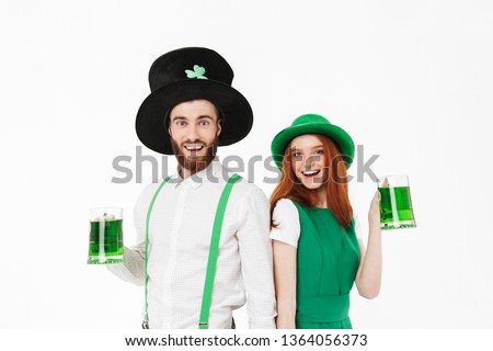 Happy young couple wearing costumes, celebrating St.Patrick 's Day isolated over white background, drinking beer
