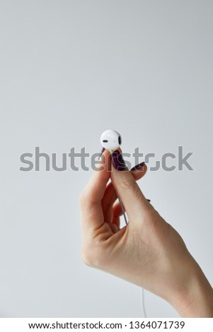 cropped view of woman holding white wired earphone isolated on grey