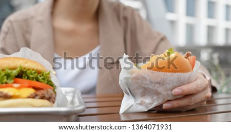 Woman eat with burger at outdoor coffee shop