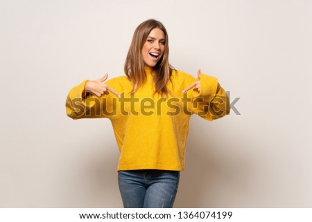 Woman with yellow sweater over isolated wall proud and self-satisfied