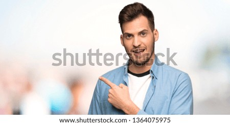 Handsome man pointing to the side to present a product at outdoors