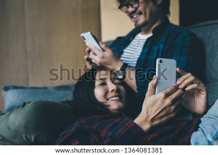using cell phone.young people wearing casual shirts.sit enjoy relax on sofa using mobile phone texting message chatting with friend.concept for technology modern communication 