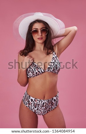 Showing off the body. Stylish beautiful young girl in bikini stands and posing in the studio.