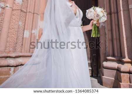 bride with wedding bouquet and veil near the church