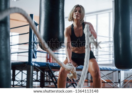 Hard working. Blonde sport woman have exercise with ropes in the gym. Strong female.
