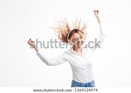 Wireless connection.Young woman listening loud funny music on the radio in headphones. Glad girl in casual clothes posing with hair waving and laughing. having fun on white studio background