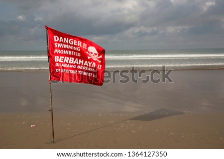 Red flag indicating in English and Indonesian language; Danger swimming prohibited, because of strong currents