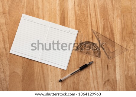 Blank notebook, pen and architect drawing tool such as protractor and set square ruler on wooden desk 