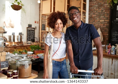 Portrait Of Couple With Trolley Buying Fresh Fruit And Vegetables In Plastic Free Grocery Store