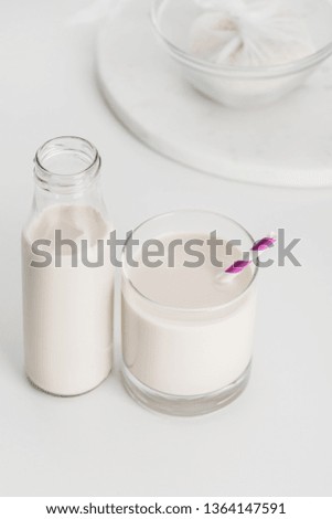 selective focus of rice milk in bottle and glass with rice in cheesecloth on background