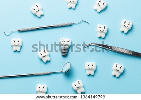 Healthy white teeth and implants are smiling on blue background and dentist tools mirror, hook