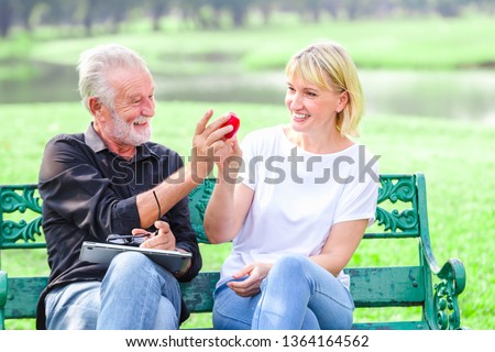 Happy senior couple in park holding heart in love valentine day concept