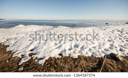 Snow pile on the beach, hill. Large snow drift isolated on a blue sky background, 
outdoor view of ice blocks at frozen finland lake in winter