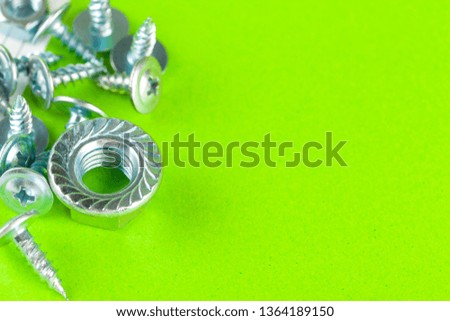 Top view of stainless steel bolts or iron nails on bright green background 