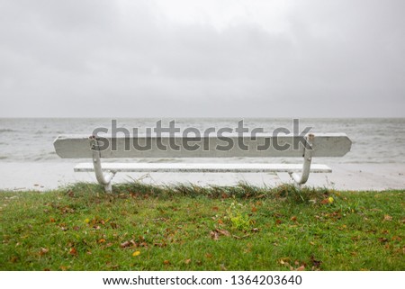 White wooden bench on the shore of lagoon on calm rainy day in Curonian Spit, Lithuania.