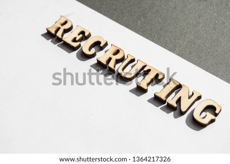 The word recruiting is written in wooden letters on a white background, the concept of hiring employees, recruitment in business and army