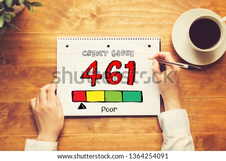 Poor credit score theme with a person holding a pen on a wooden desk